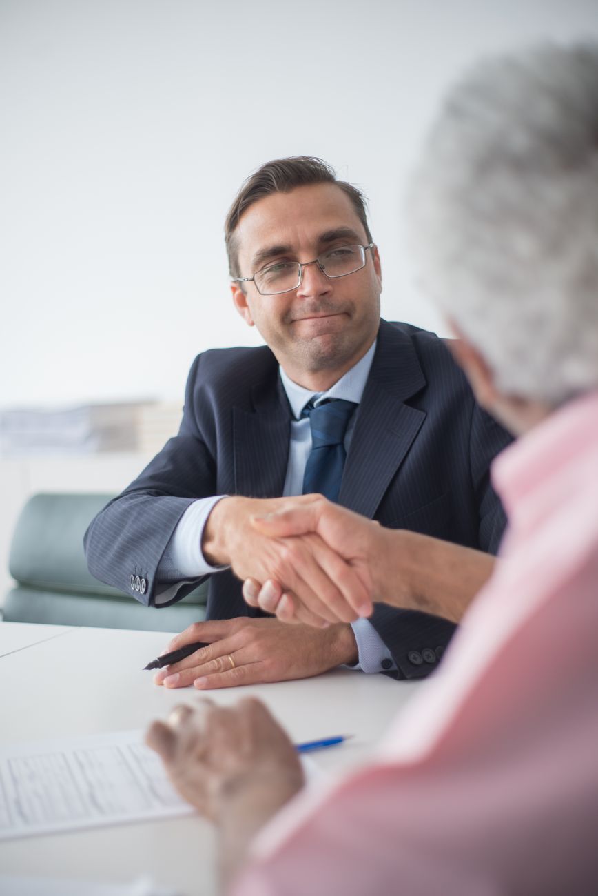 man in black suit jacket wearing eyeglasses shaking hands with a man